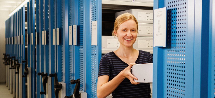 Eine Frau zieht etwas aus dem Lagerschrank im Kreisarchiv hervor. Foto: Thomas Grimm
