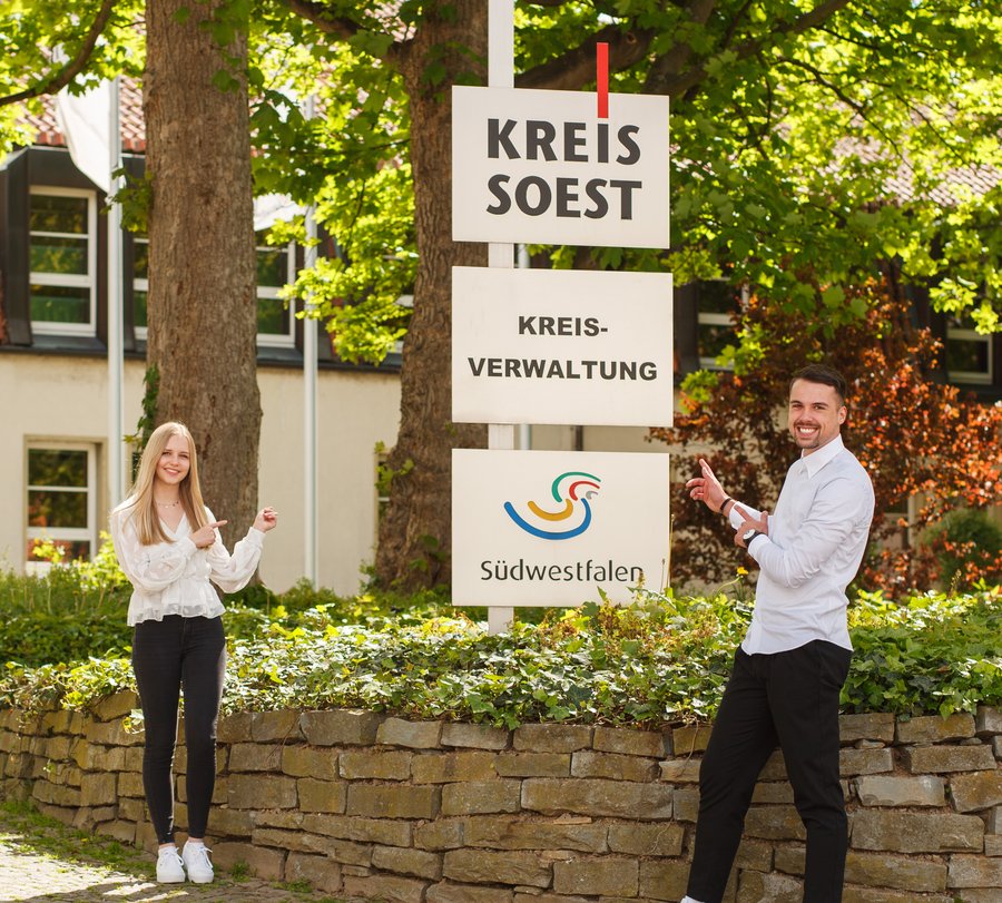 Zwei Studierende posieren vor den Schildern vor dem Haupteingang. Foto: M. Petrilli