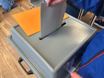 Stimmzettel, der in eine Wahlurne geworfen wird. Foto: Birgit Kalle/Kreis Soest