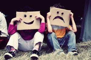 Zwei Kinder, mit einer lächelnden und einer weinenden Maske vor dem Gesicht. Foto: © sarahbrooks - Fotolia