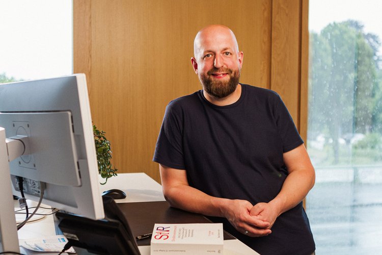 Verwaltungswirt. Foto: Thomas Grimm Ein Mann steht angelehnt an einen Schreibtisch. Vor ihm liegen mehrere Gesetze. Foto: Thomas Grimm