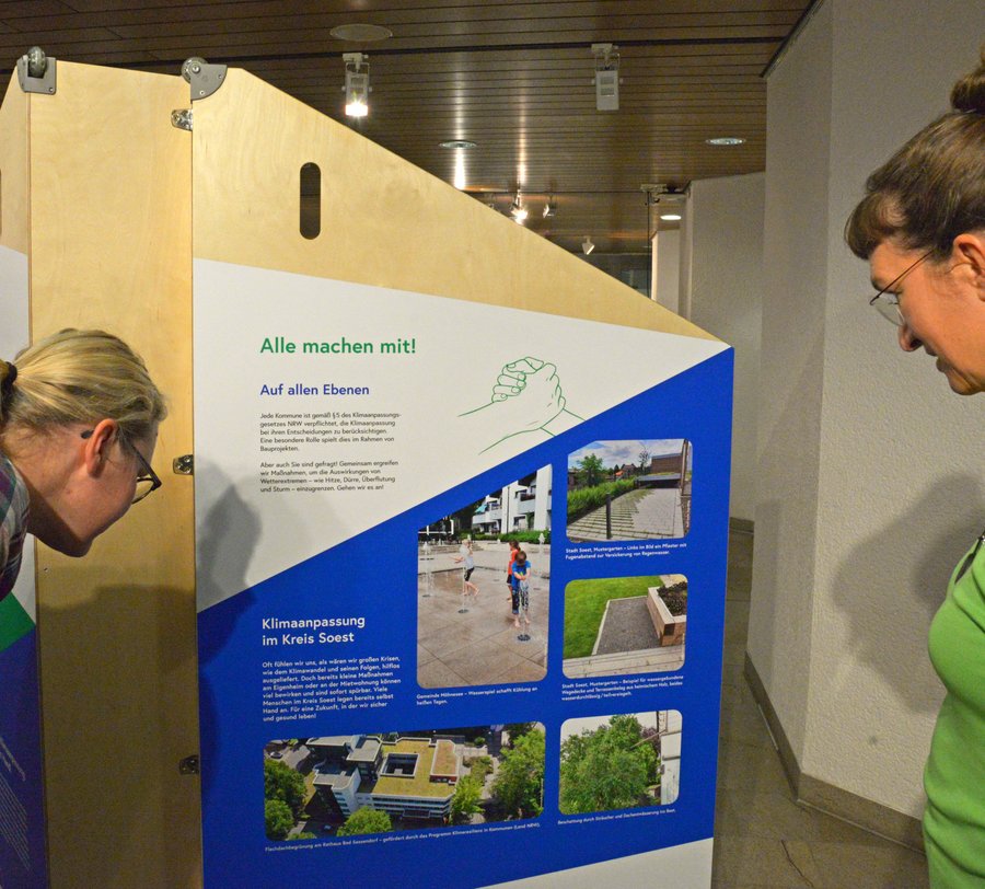 Bei Personen betrachten den Aufsteller zur Ausstellung „Aufgepasst. Angepasst!“. Foto: Kira Hönicke/ Kreis Soest