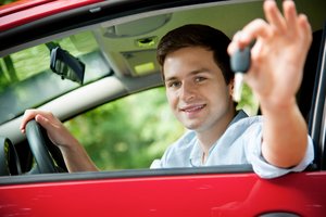 Junger Mann sitzt im Auto und hält einen Autoschlüssel hoch. Foto: © Alexander Raths - Fotolia.com