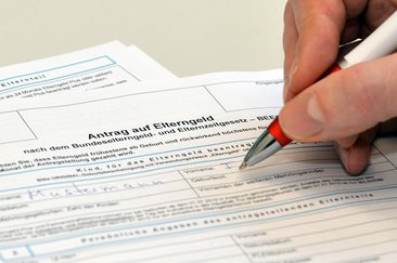 Foto: Kugelschreiber in einer Hand über einem Elterngeldantrag. Judith Wedderwille/Kreis Soest