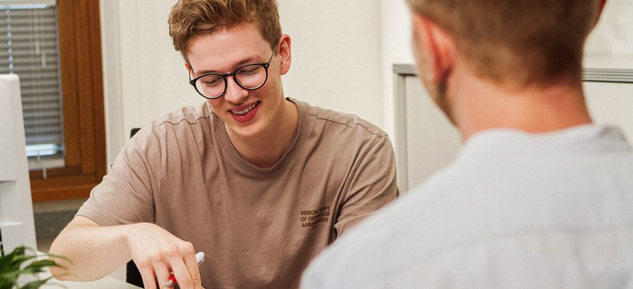 Bachelor of Arts - Soziale Arbeit. Foto: Thomas Grimm Ein Mann blättert in seinen Unterlagen und berät einen Kunden. Foto: Thomas Grimm