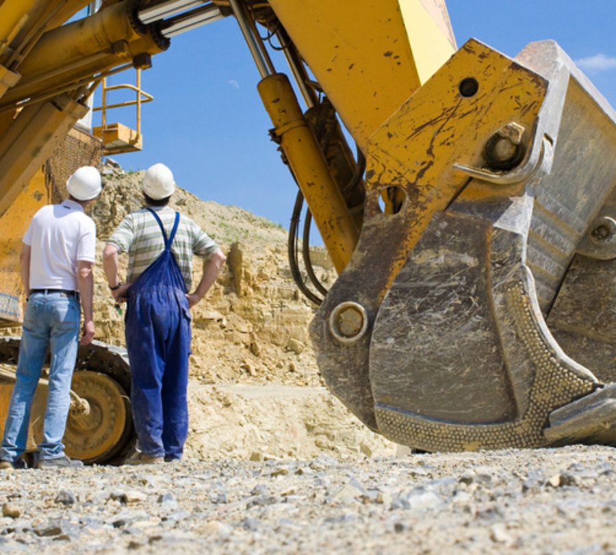 Arbeiter vor einem großen Bagger in einem Steinbruch. Foto: © fineart-collection - Fotolia.com
