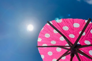 Ein pinker Cocktailschirm mit Punkten ist im Vordergrund zu sehen. Die Sonne scheint am Himmel. Foto: Judith Wedderwille/ Kreis Soest