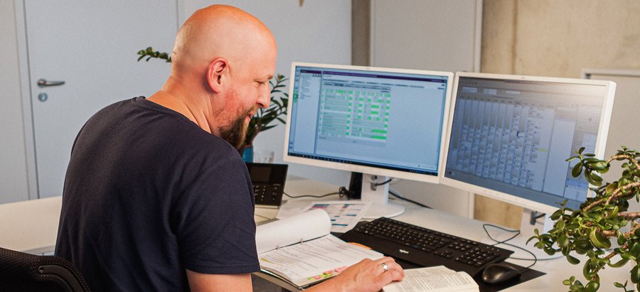 Verwaltungswirt. Foto: Thomas Grimm Ein Mann schaut in ein Gesetzbuch und bearbeitet nebenbei digital Anträge. Foto: Thomas Grimm