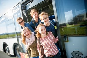 Entdeckerbus. Foto: RLG Fünf Kinder und Jugendliche stehen in der Tür eines Busses und schauen nach vorn. Foto: RLG