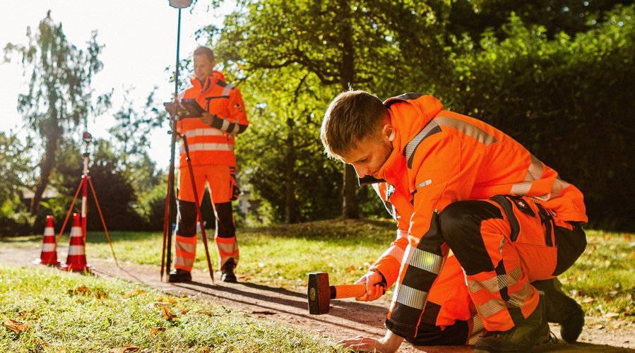 Ein Mann setzt einen Grenzstein. Ein anderer Mann dokumentiert dies technisch. Foto: Thomas Grimm
