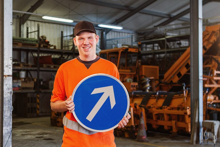 Ein Mann hält ein Verkehrsschild mit einem Pfeil, der nach oben zeigt. Foto: Thomas Grimm