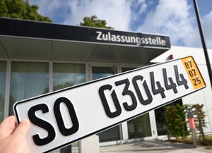 KfZ-Zulassung. Foto: Judith Wedderwille/ Kreis Soest Ein Schild mit einem Soester Kennzeichen, im Hintergrund ist das Gebäude einer Zulassungsstelle. Foto: Judith Wedderwille/ Kreis Soest